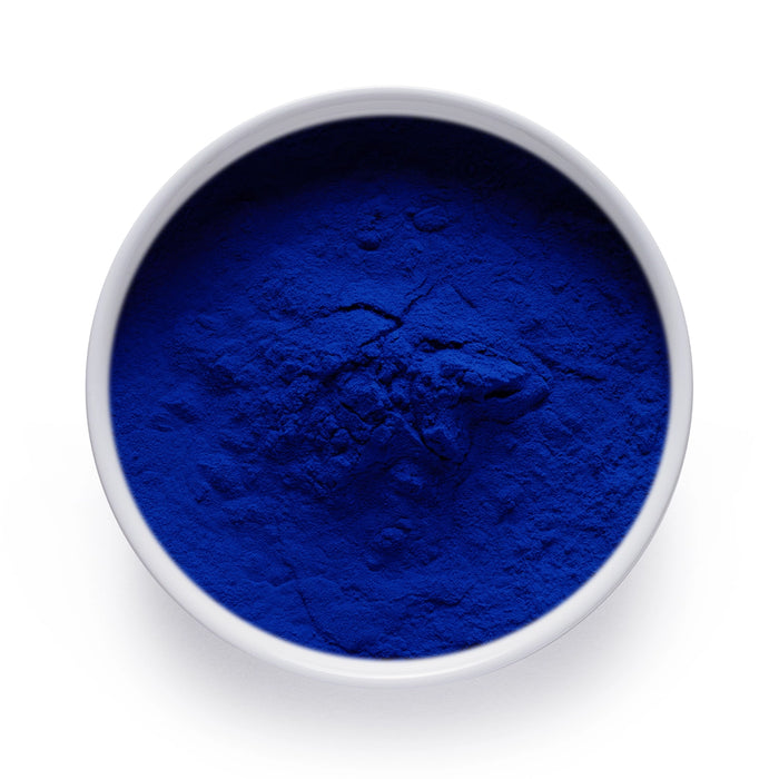 Bột phycocyanin màu xanh lam đậm đựng trong bát sứ trắng.