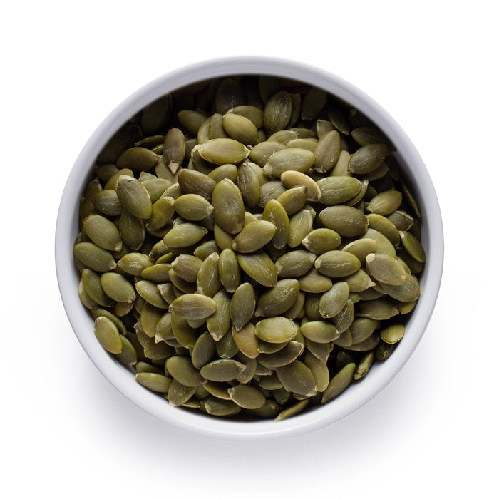 Dolce Superfoods organic pumpkin seeds in white bowl on white background