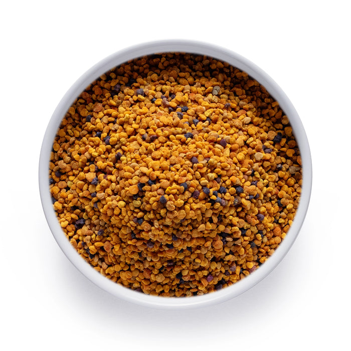 Bulk organic bee pollen in a white bowl, golden multicolor granules sold wholesale by Dolce Superfoods