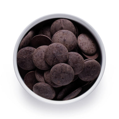 Top-down view of bulk organic cacao paste wafers in a white bowl, rich dark chocolate discs for wholesale foodservice and ingredient use.