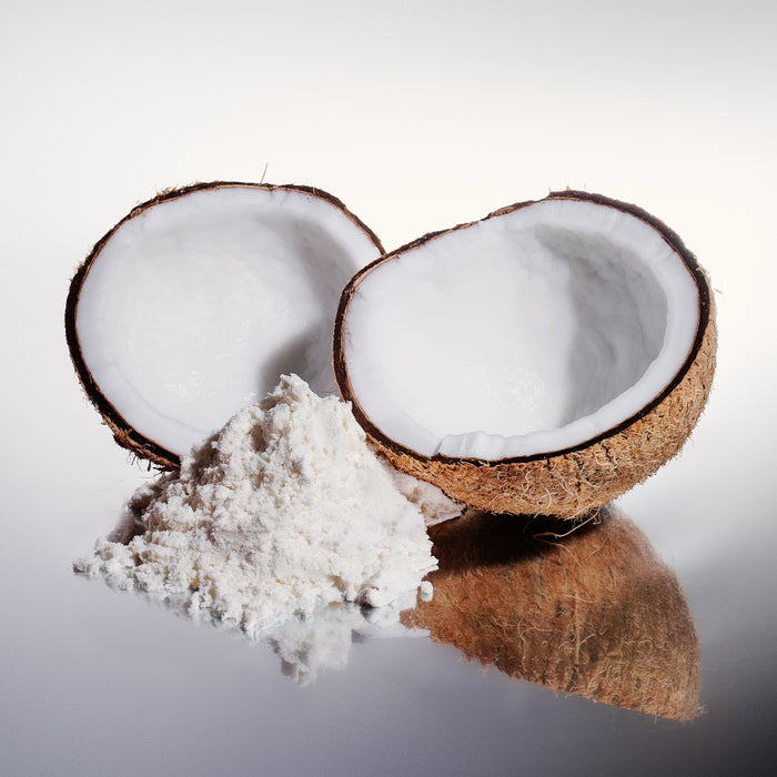 Bulk organic MCT oil powder made from coconut, shown with cracked coconuts on a clean white background.