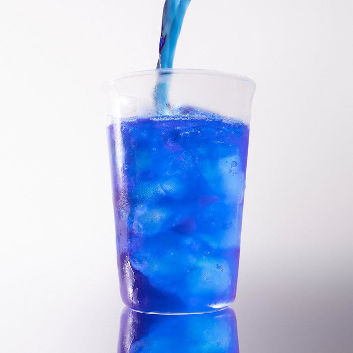 Dolce Superfoods blue spirulina drink poured over ice in clear cup