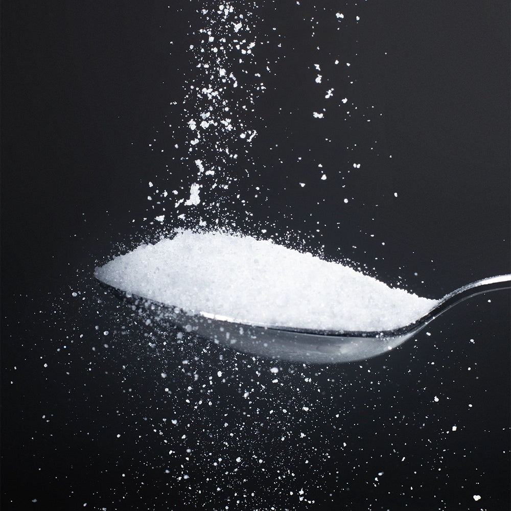 Pure glycine powder cascading onto a silver spoon against a dark background — Dolce Superfoods bulk glycine amino acid supplement