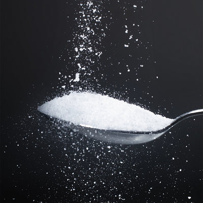 Pure glycine powder cascading onto a silver spoon against a dark background — Dolce Superfoods bulk glycine amino acid supplement