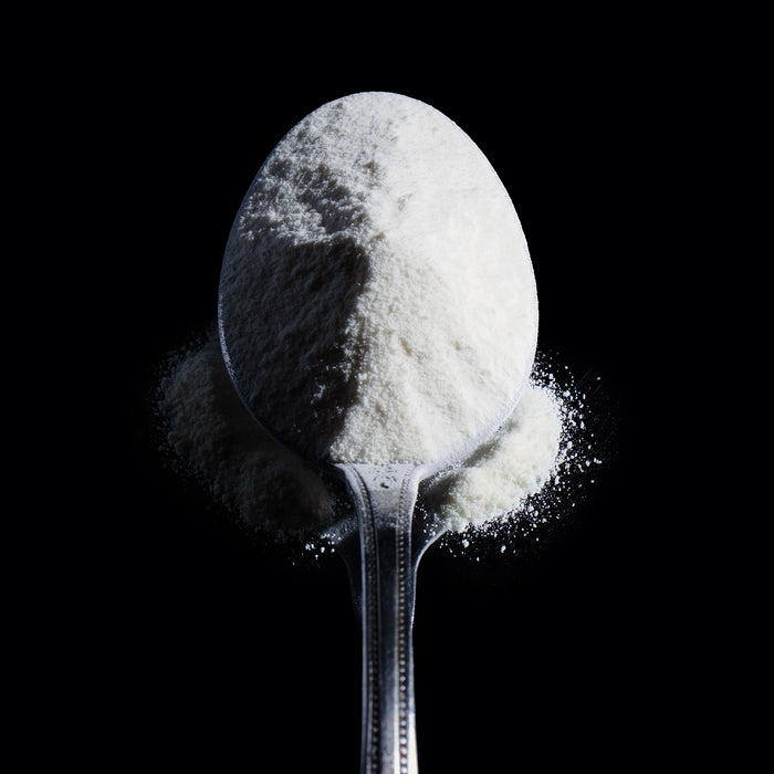 Dolce Superfoods grass-fed collagen peptides powder in spoon on black background