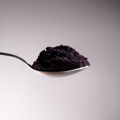 Dolce Superfoods organic açaí powder on spoon against neutral background