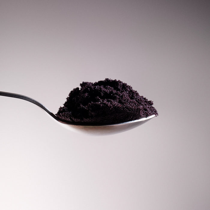 Dolce Superfoods organic açaí powder on spoon against neutral background