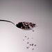 Dolce Superfoods organic cacao nibs on metal spoon with falling pieces