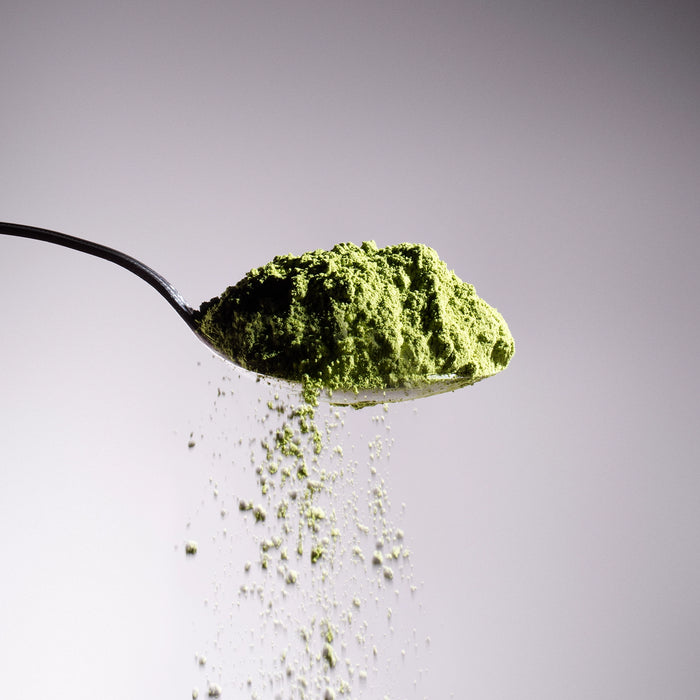 Dolce Superfoods organic ceremonial matcha powder cascading from spoon
