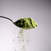Dolce Superfoods organic ceremonial matcha powder cascading from spoon