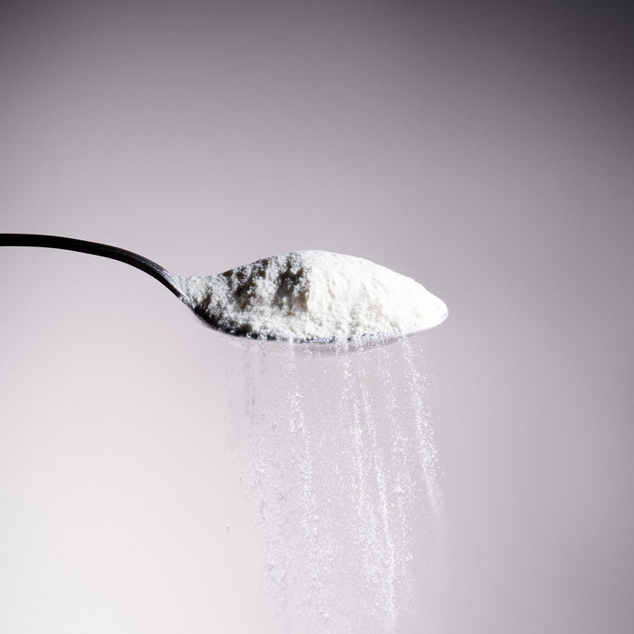 Dolce Superfoods organic coconut water powder cascading off of a metal spoon