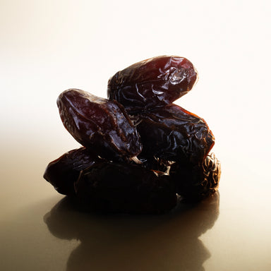 Close-up of organic Medjool dates stacked in soft natural light, showcasing texture and richness