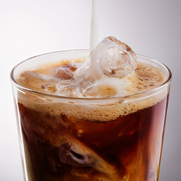 Dolce Superfoods organic instant coffee served iced with milk pouring into glass