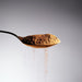 Dolce Superfoods organic instant coffee powder on spoon against light background