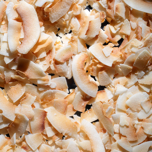 Dolce Superfoods organic toasted coconut chips texture close up against a dark background
