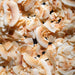 Dolce Superfoods organic toasted coconut chips texture close up against a dark background