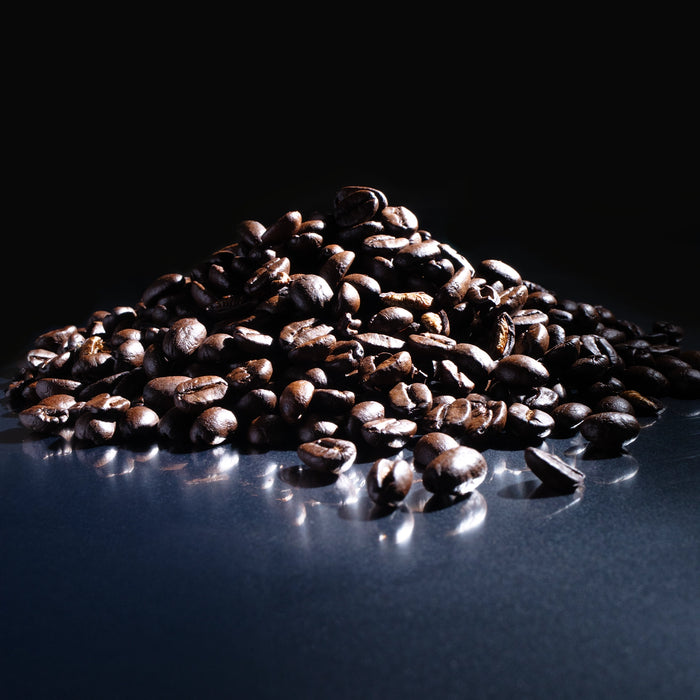 Dolce Superfoods organic whole bean coffee beans piled on reflective surface against dark background